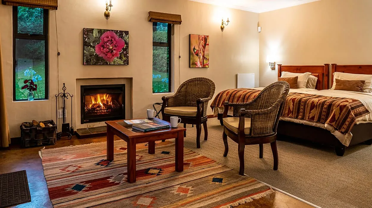 Cozy bedroom with fireplace two chairs and two beds with colorful blankets