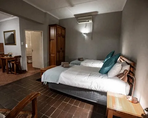 Bedroom with two single beds wooden furniture and tiled floor