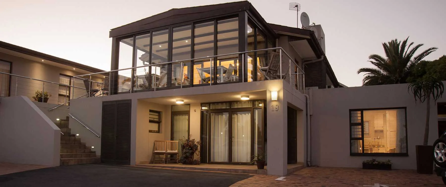 Modern twostory house with large windows and balcony at dusk