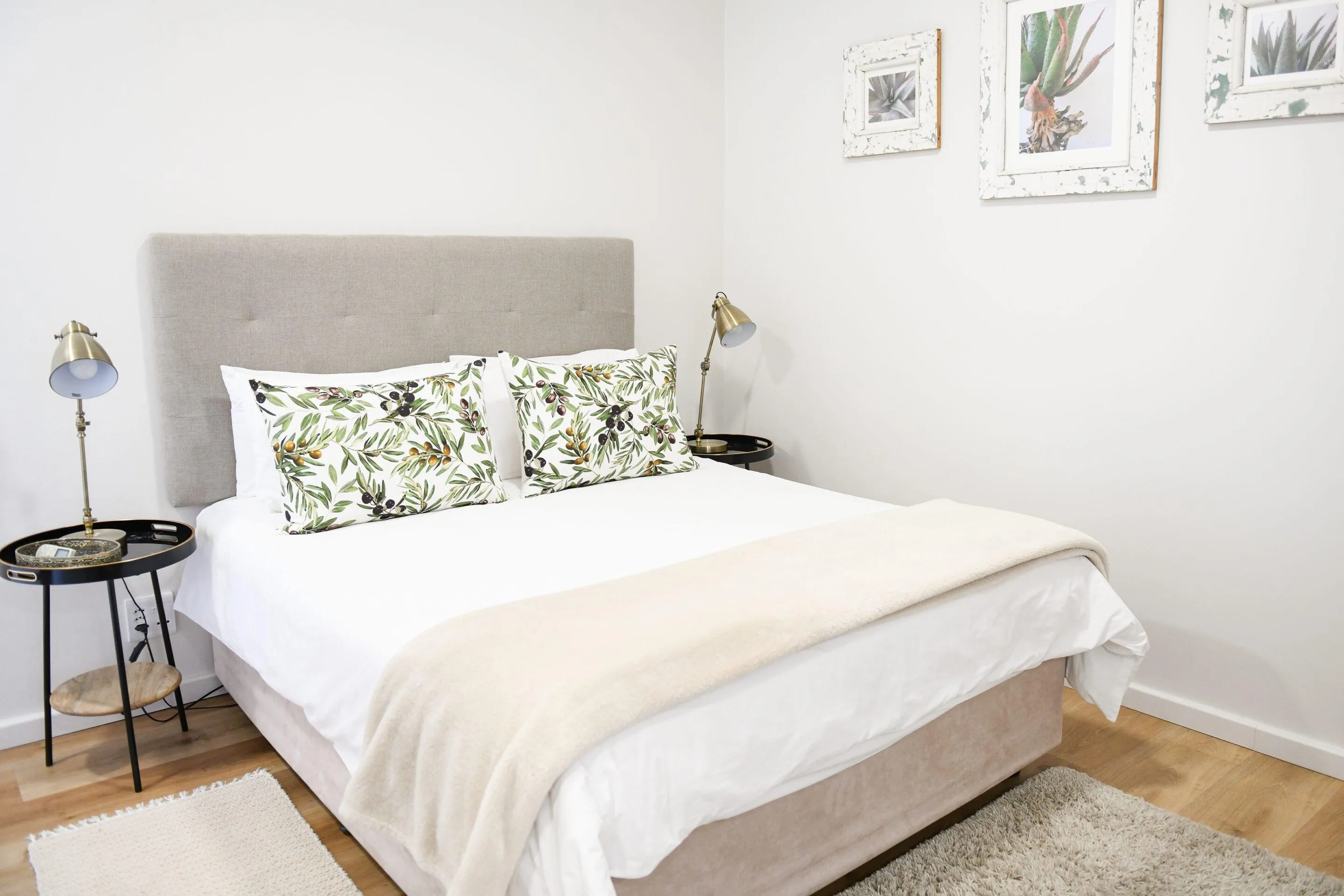 Neat bedroom with a double bed floral pillows and bedside tables with lamps