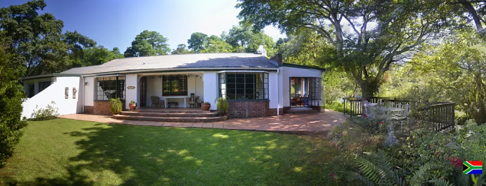 White house with large windows surrounded by trees and a wellmaintained lawn