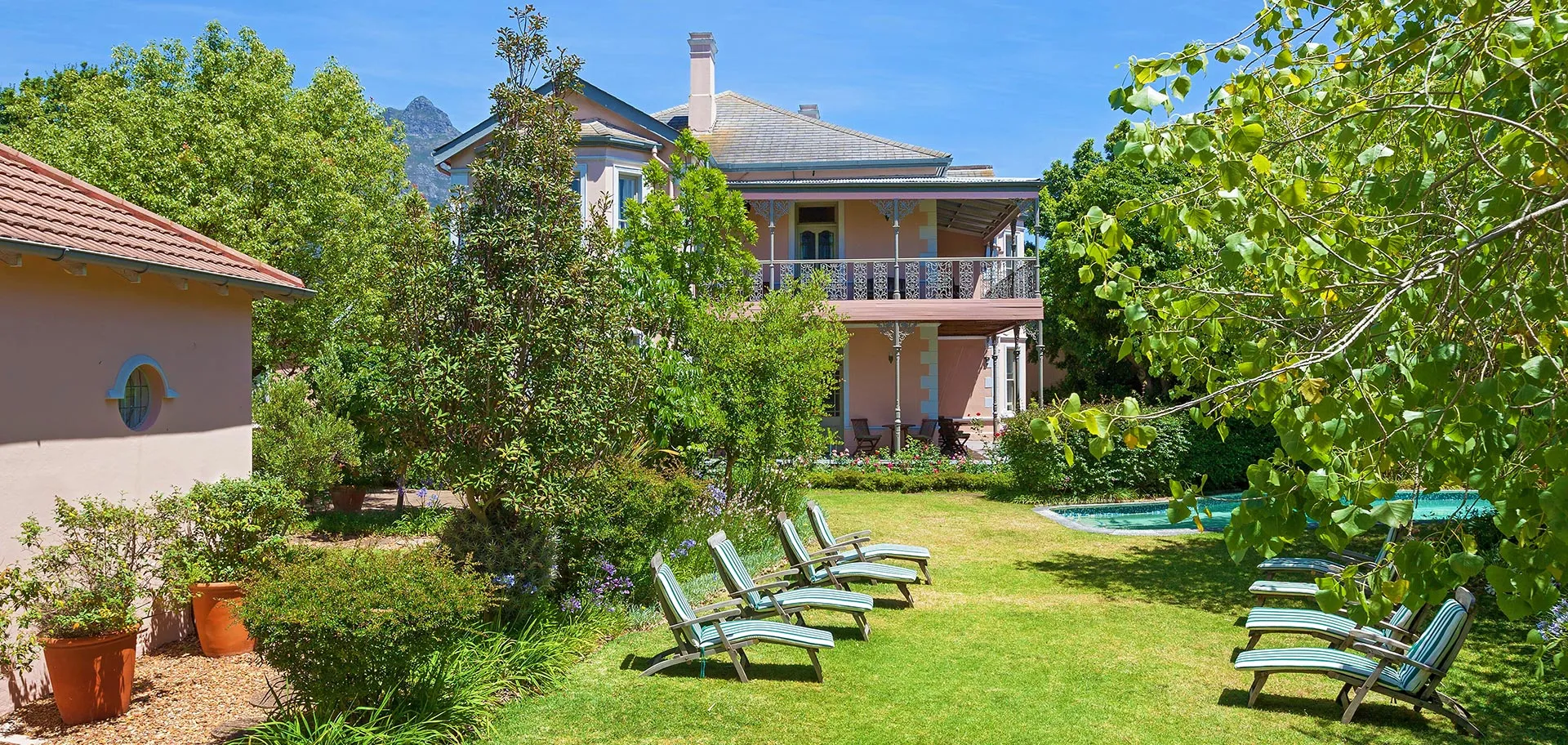 Garden with lounge chairs trees and a twostory house in the background