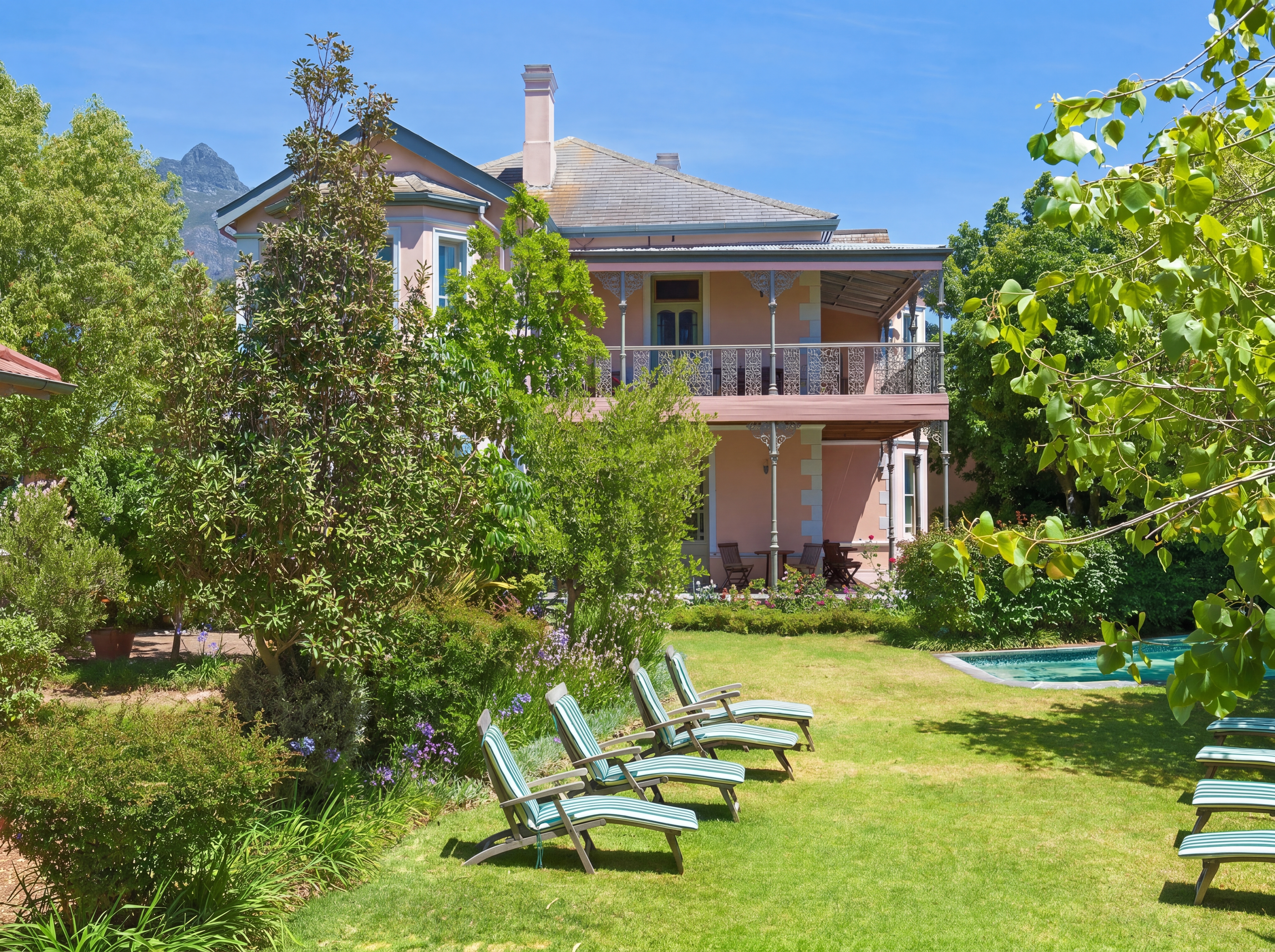 Garden with lounge chairs trees and a twostory house in the background