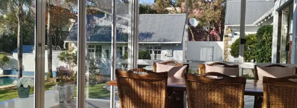 Dining area with wicker chairs large windows and view of garden and buildings