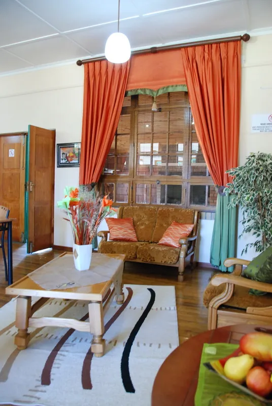 Living room with wooden furniture orange curtains and a large window