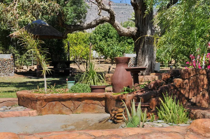Garden with large terracotta pots plants and stone features in a natural setting