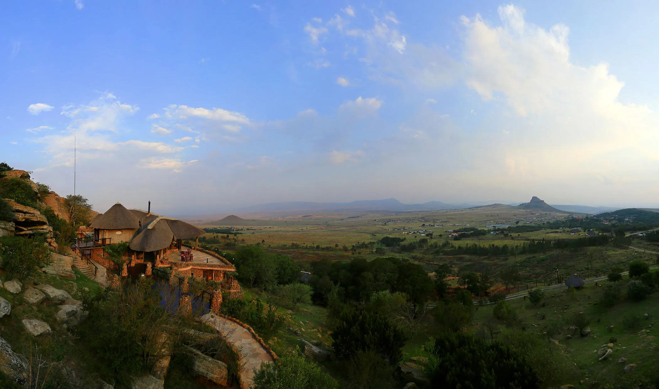 Scenic view of a lodge with a thatched roof overlooking a vast landscape