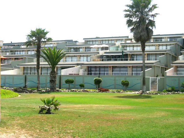 Modern apartment complex with palm trees and wellmaintained lawn in front
