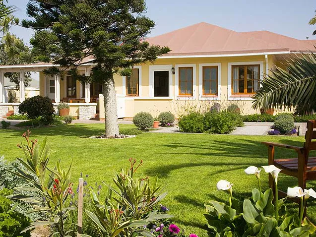 A singlestory house with a garden trees and flowers in front
