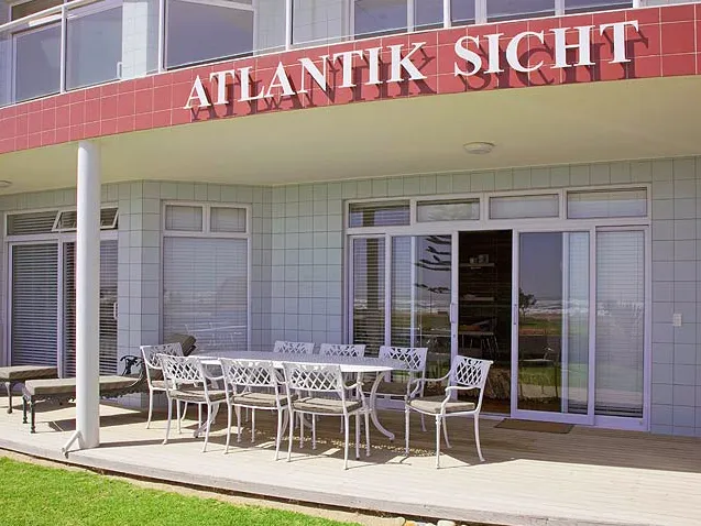 Patio with white metal furniture in front of a building named ATLANTIK SICHT