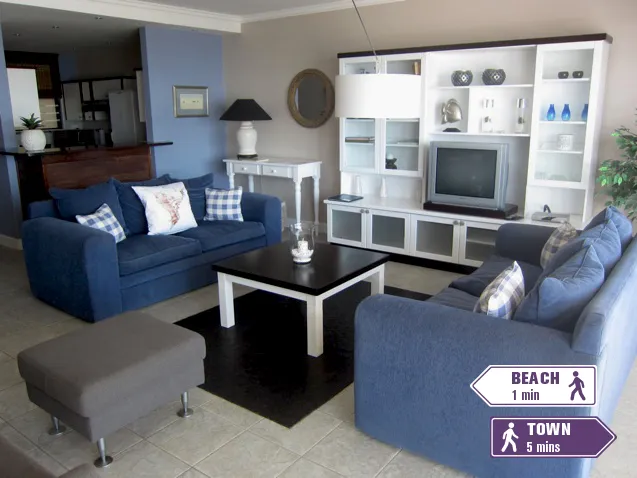 Blue living room with white furniture and signs indicating beach and town distances