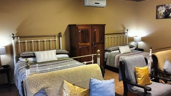 Bedroom with two beds wooden wardrobe and seating area with yellow cushions
