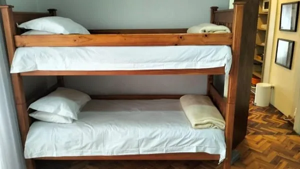 Wooden bunk bed with white bedding in a room with wooden floor
