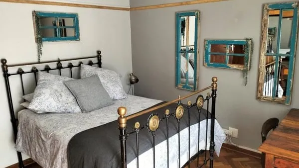 A neatly made bed in a bedroom with vintage mirrors on the walls