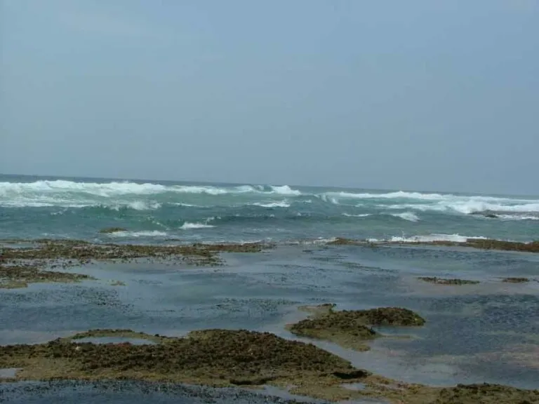 Rocky shoreline with waves crashing in the ocean under a clear sky