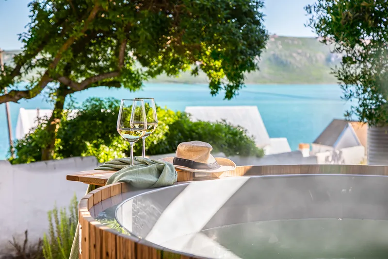 Hot tub with wine glass hat and scenic lake view in the background
