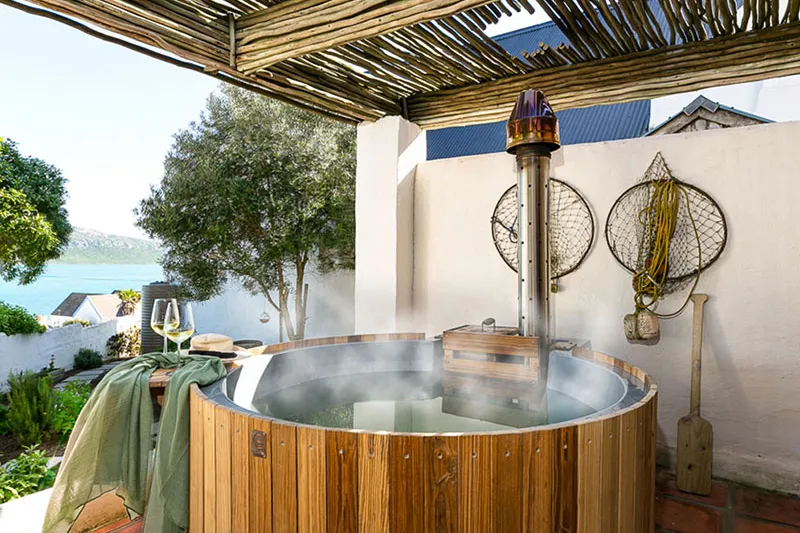 Wooden hot tub with steam outdoor setting scenic view wine glass on table