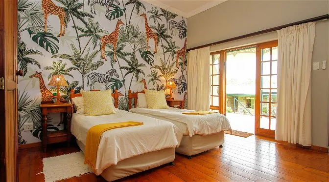 Bedroom with junglethemed wallpaper two beds and large sliding glass doors