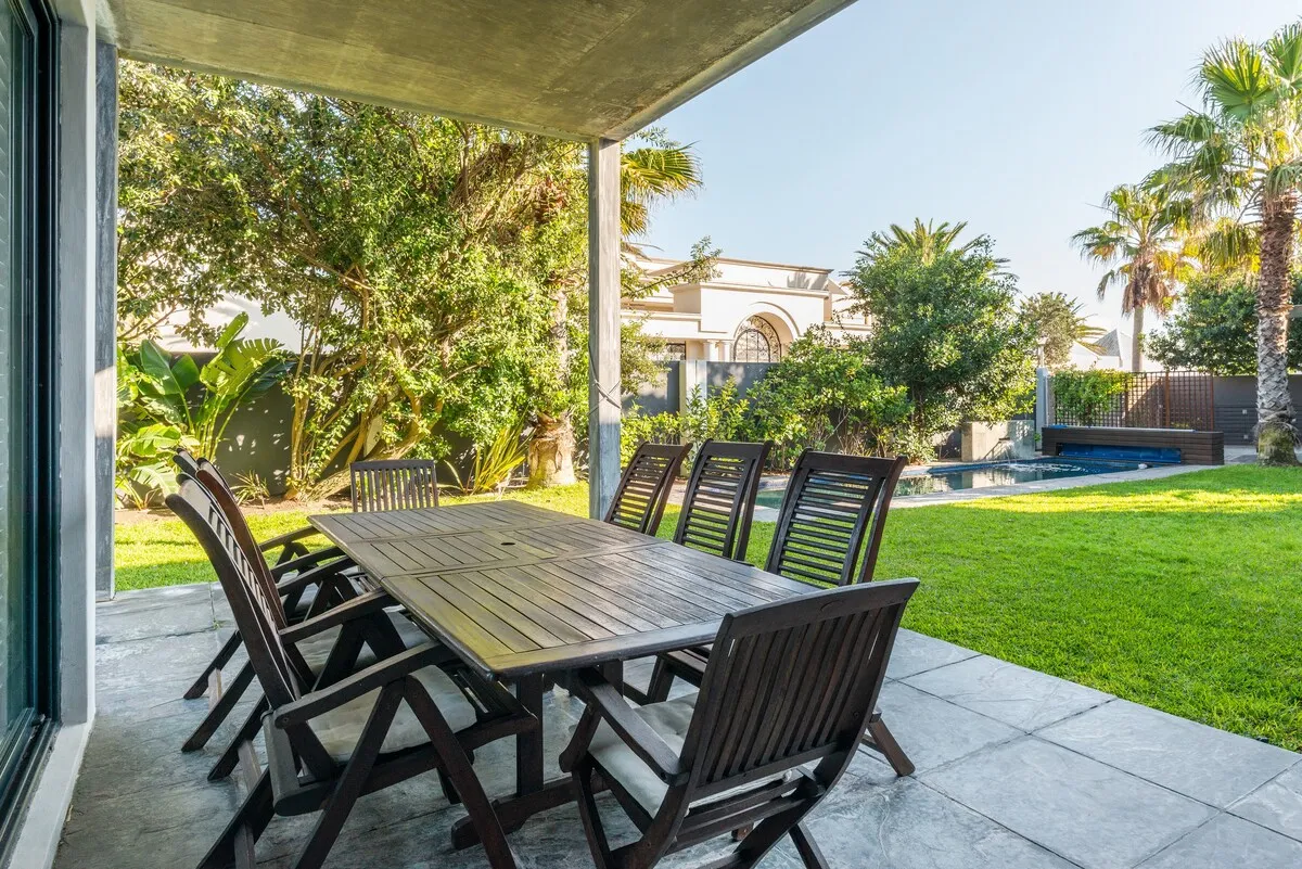 Outdoor dining area with wooden table and chairs on a patio with green lawn