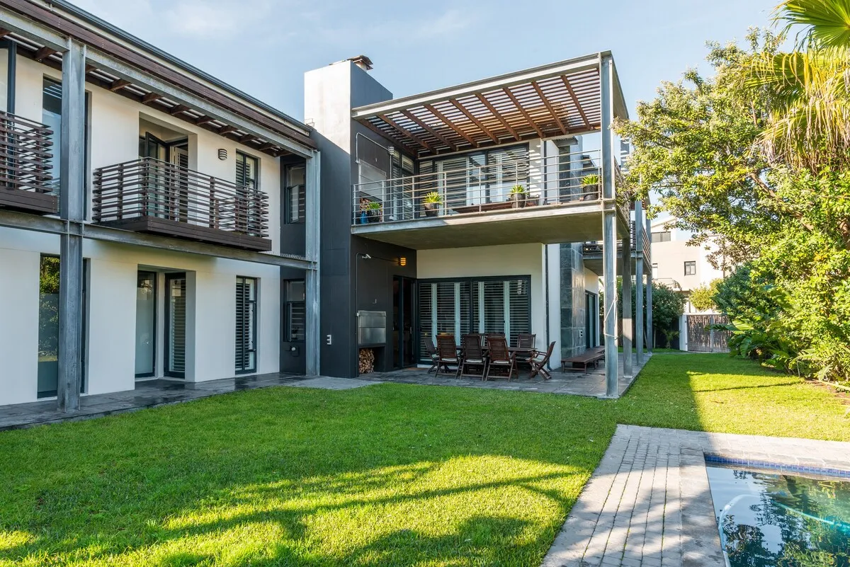 Modern twostory house with balcony lawn and swimming pool in sunny garden
