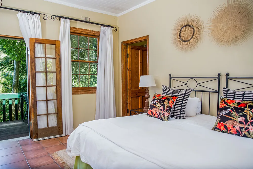 Bedroom with a large bed floral pillows and open doors to a balcony