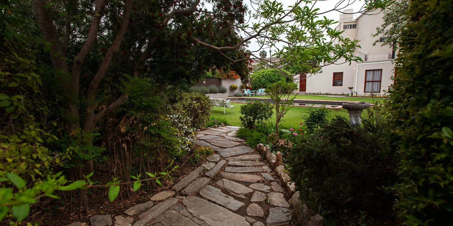 Stone path through a garden leading to a house with greenery on both sides