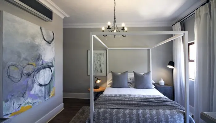 Modern bedroom with a fourposter bed abstract art and a chandelier
