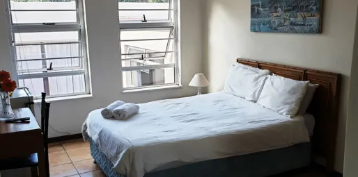 Bright bedroom with white bed desk windows and abstract wall art