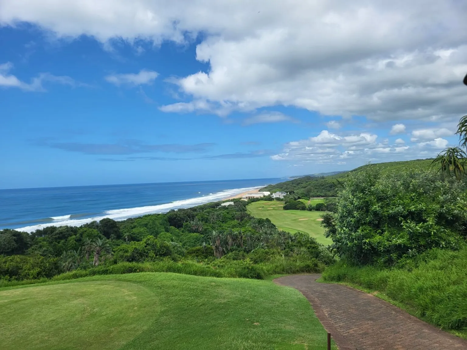 Scenic view of ocean beach and golf course with green landscape