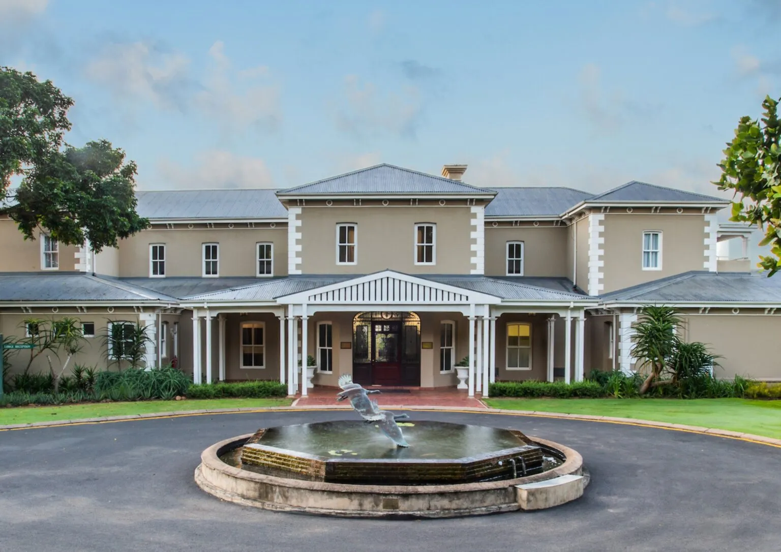 Large elegant twostory house with a fountain in front and a circular driveway