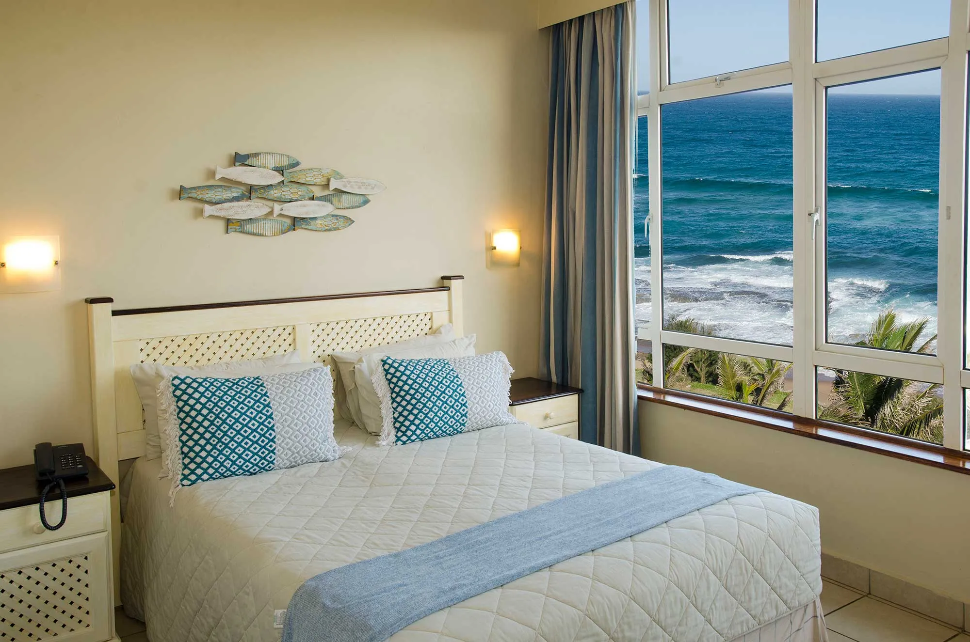 Bedroom with large windows overlooking the ocean decorated with blue and white accents