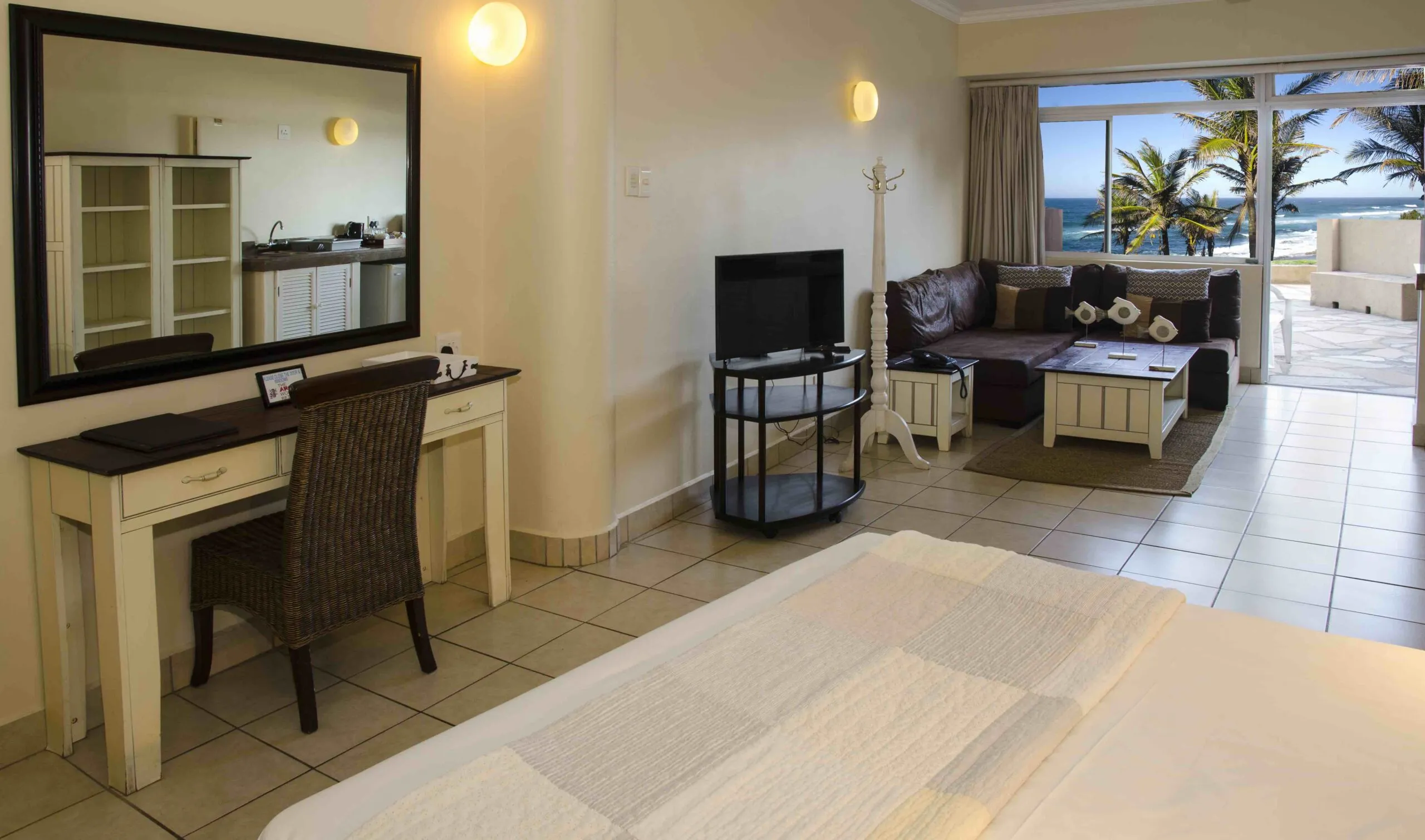 Hotel room with bed desk sofa and ocean view through sliding glass doors
