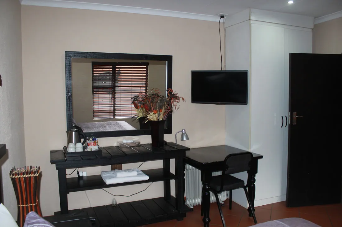 Bedroom with dresser mirror TV and desk with chair