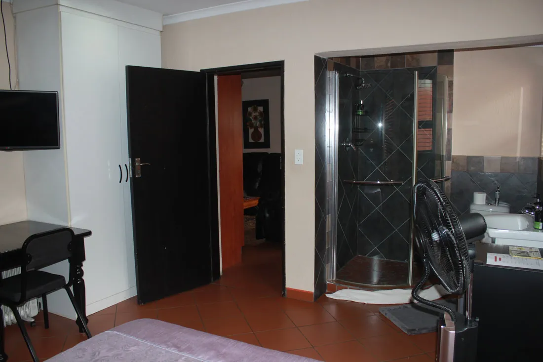 Bedroom with open door to bathroom TV desk and fan