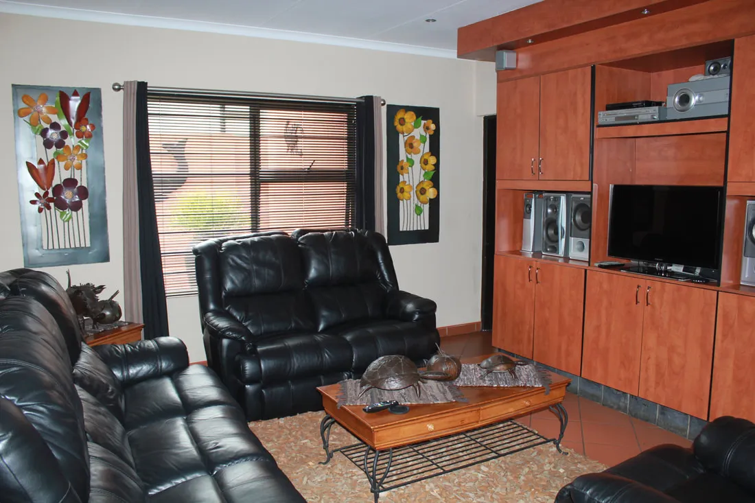 Living room with black leather furniture TV and decorative wall art