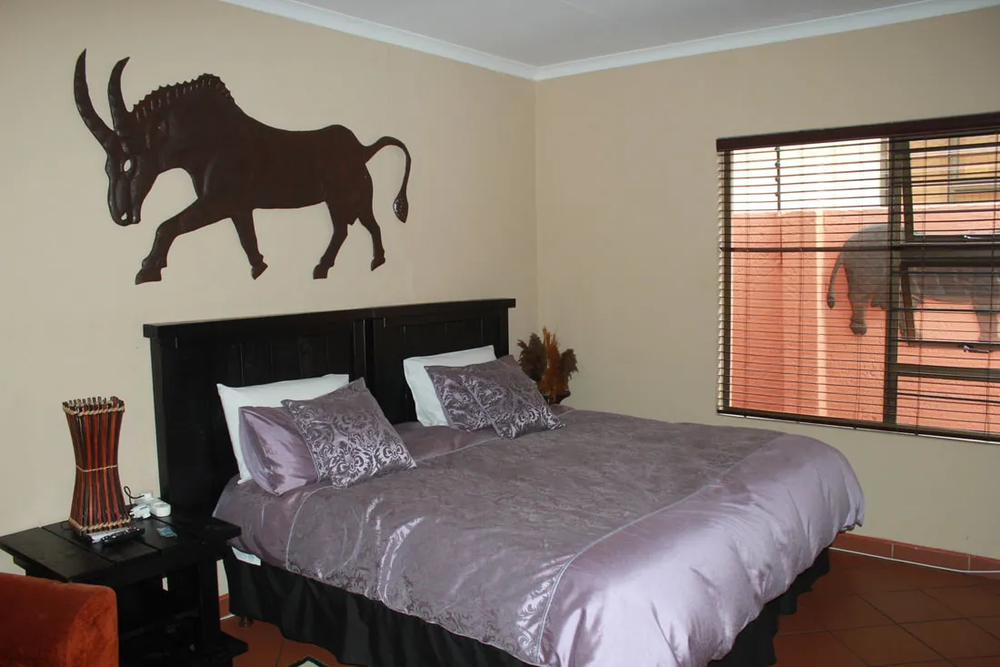 Bedroom with a large bed bull silhouette on wall and elephant outside window
