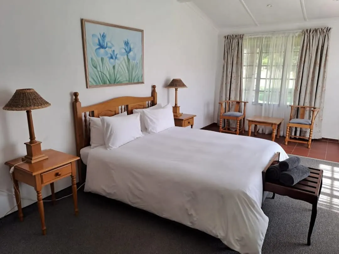 Bedroom with double bed two nightstands two chairs and floral artwork on wall