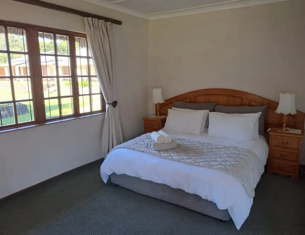 Cozy bedroom with a large bed wooden headboard and a sunny window view