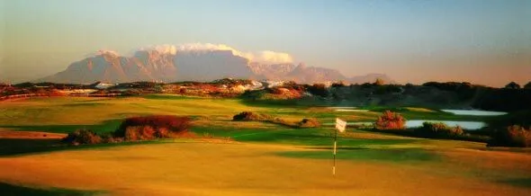 Golf course with mountains in the background during sunset