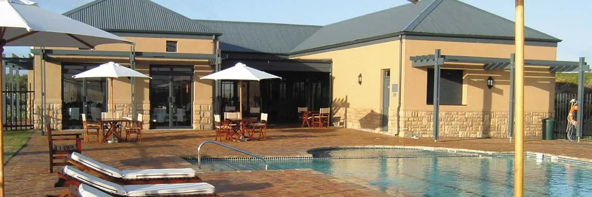 Outdoor pool area with lounge chairs umbrellas and a building in the background