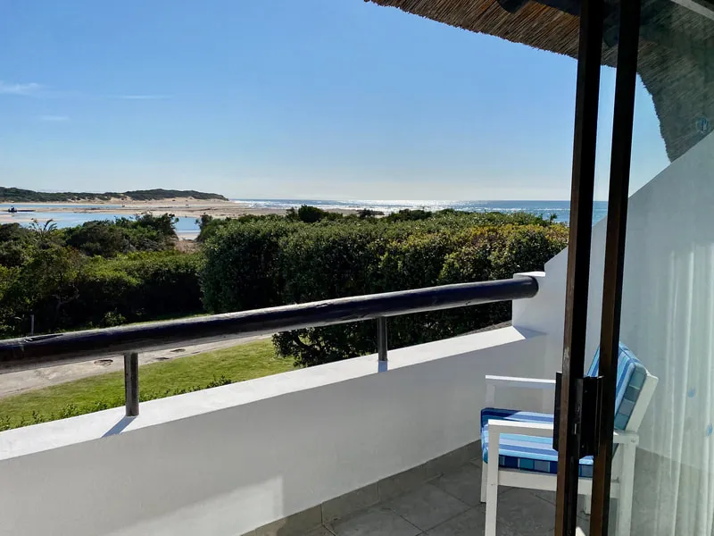 Balcony with blue chair overlooking a beach and greenery