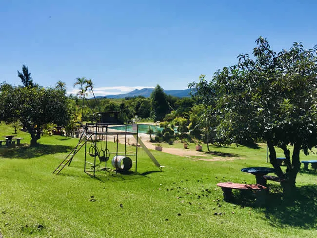 Playground with swings and slide in a grassy park with trees and mountains