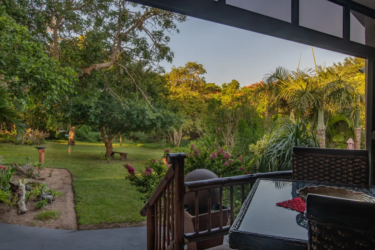 Patio with outdoor furniture overlooking a lush garden and trees