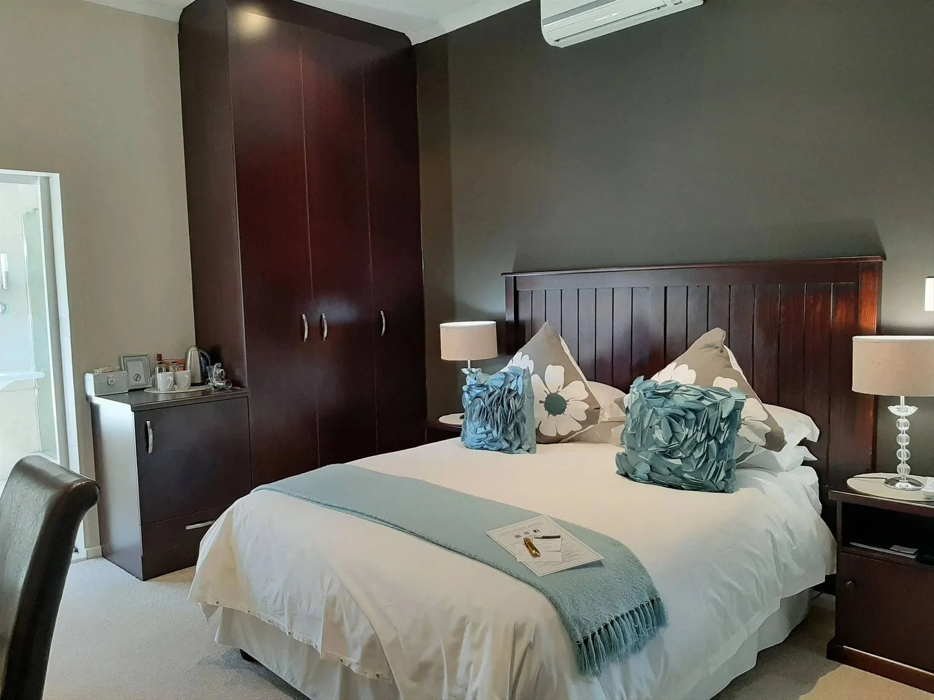 Modern bedroom with a large bed blue pillows and bedside tables with lamps