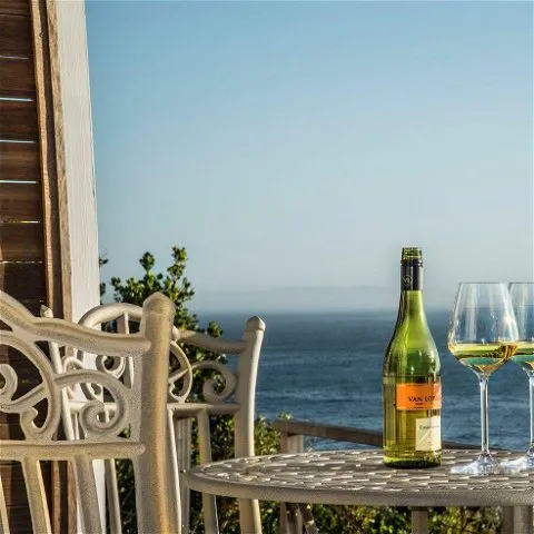 A bottle of wine and two glasses on a table with an ocean view