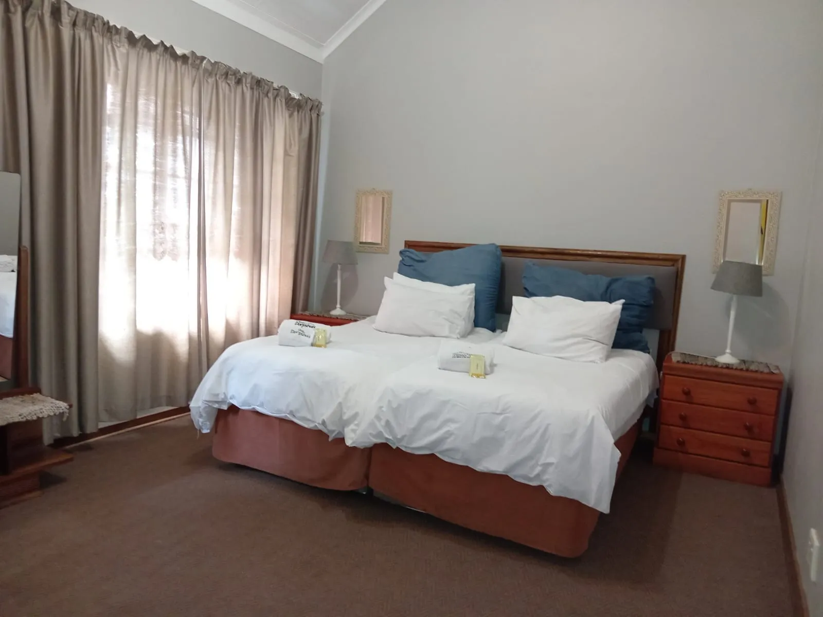 A neatly made bed in a bedroom with curtains and side tables