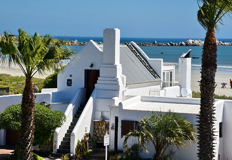 White beach house with palm trees and ocean view