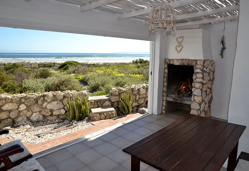 Patio with stone fireplace wooden table and ocean view