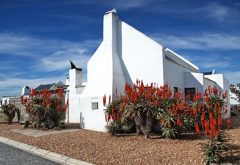 White house with red aloe plants in front clear blue sky