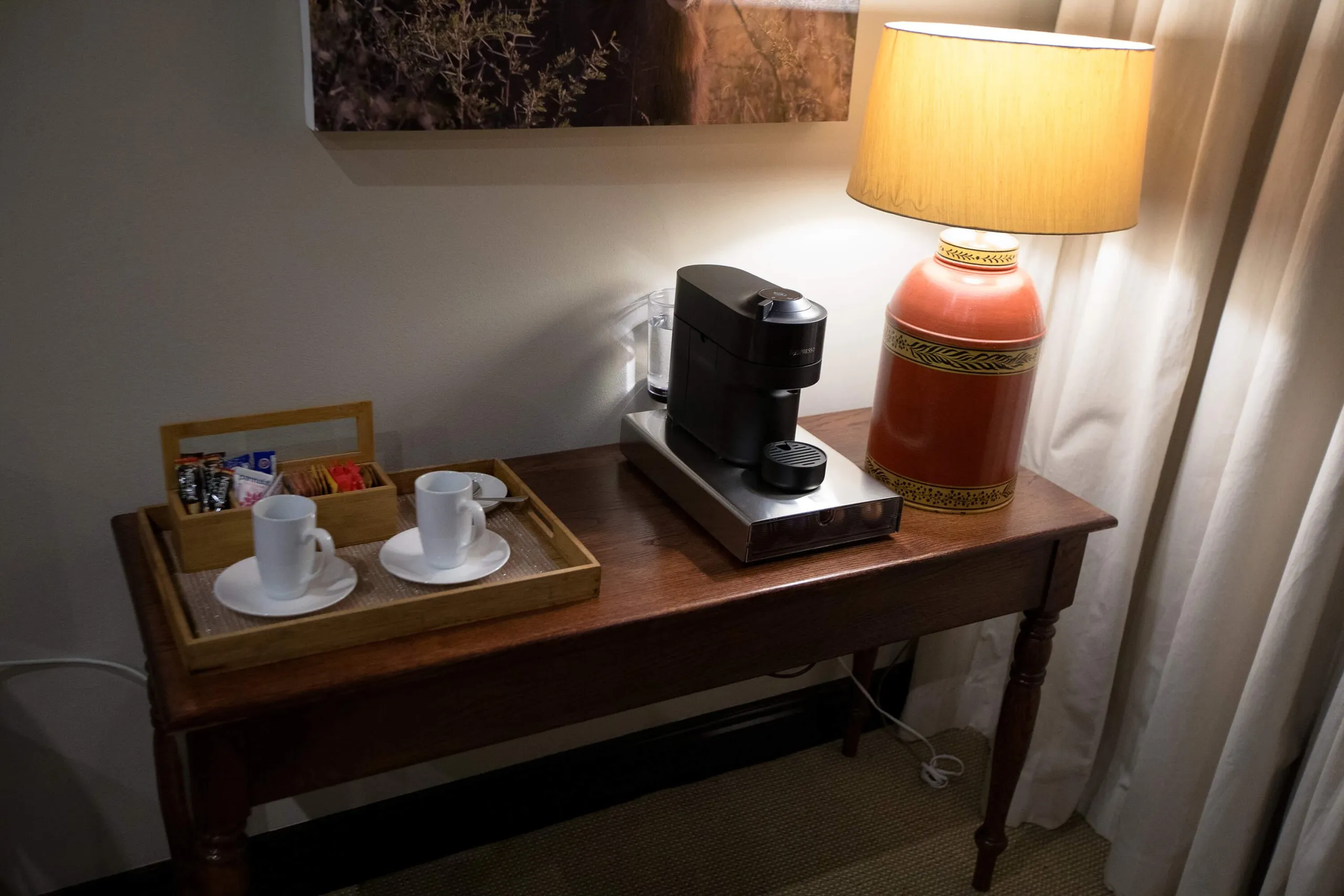 Coffee maker cups and lamp on a wooden table in a room